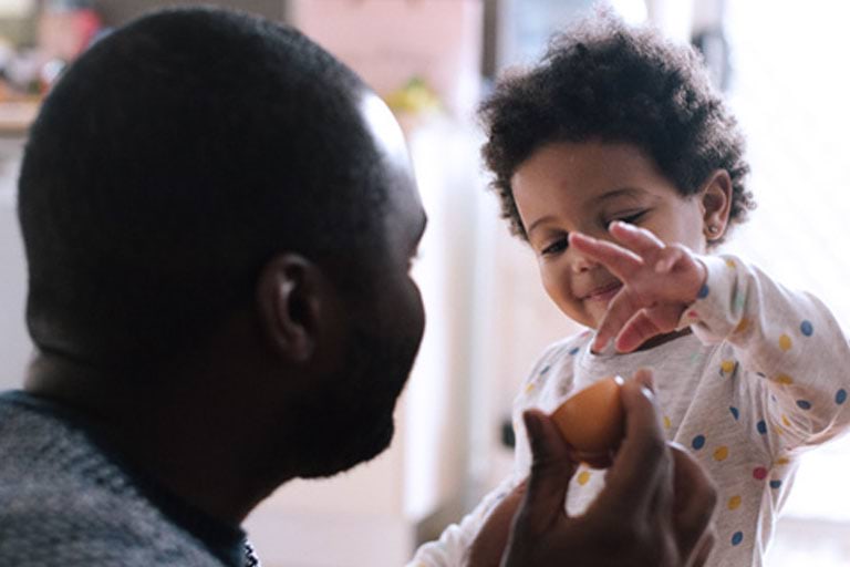 A father showing a toddler a toy